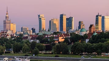 Eine Stadtlandschaft mit modernen Gebäuden, einem historischen Turm und einem Fluss, auf dem ein Boot fährt.