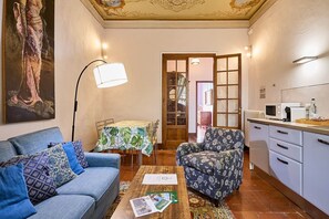 A living room with a sofa, armchair, coffee table, and a painting on the wall. - Ann Kemp apartment (Montepulciano)