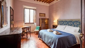 Un dormitorio con cama, escritorio, silla, armario y ventana.