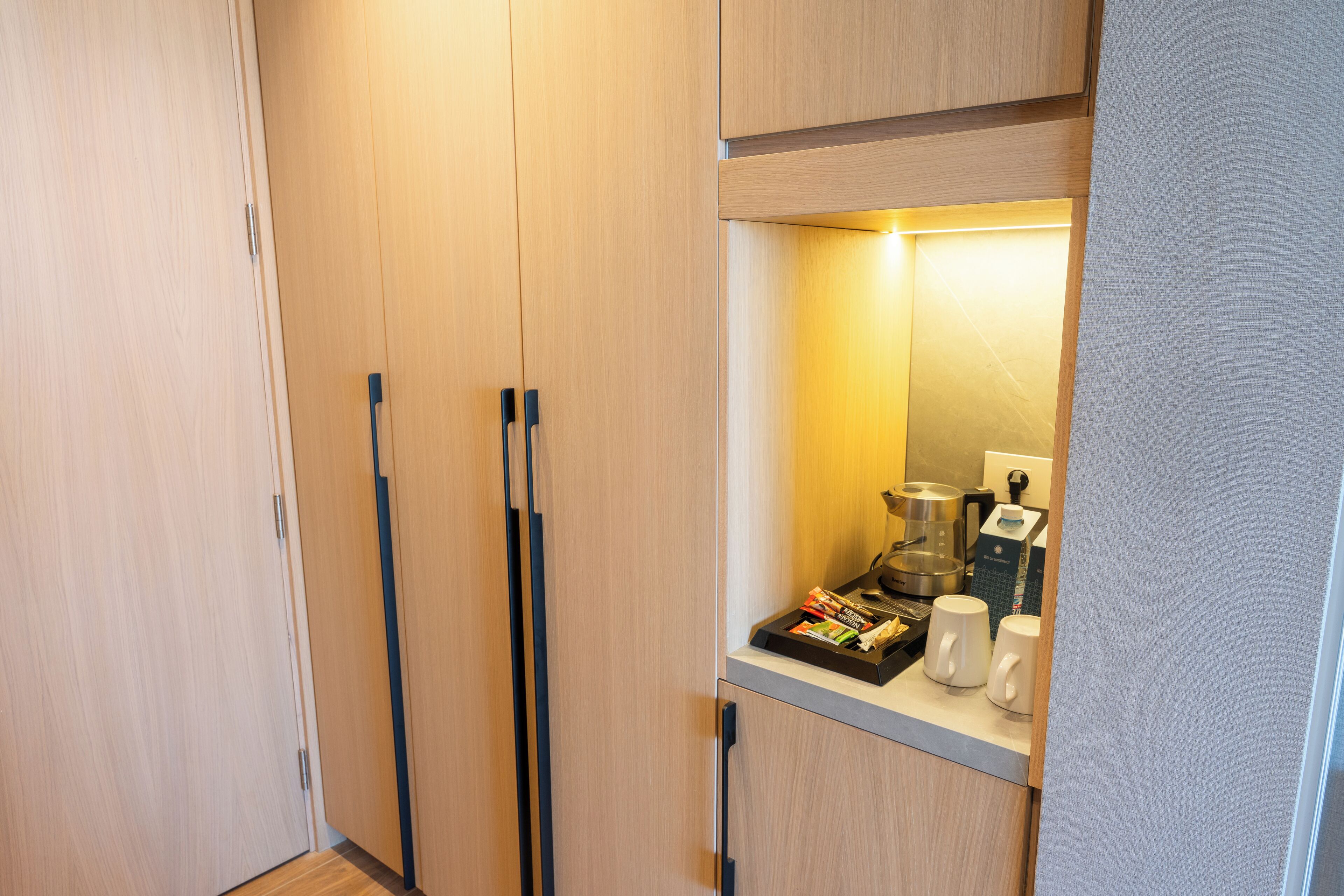 A compact kitchenette with a coffee maker, a kettle, and a tray of snacks.