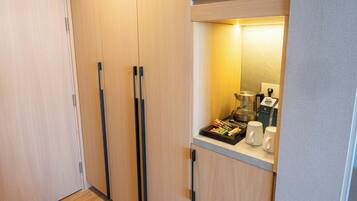 A compact kitchenette with a coffee maker, a kettle, and a tray of snacks.
