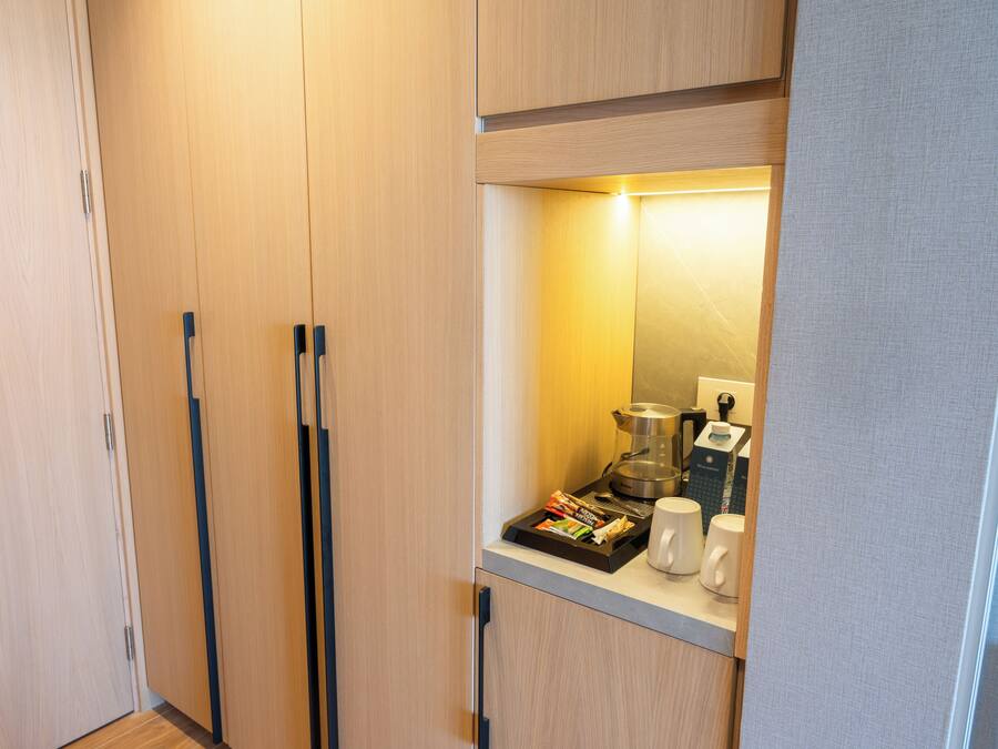 A compact kitchenette with a coffee maker, a kettle, and a tray of snacks.