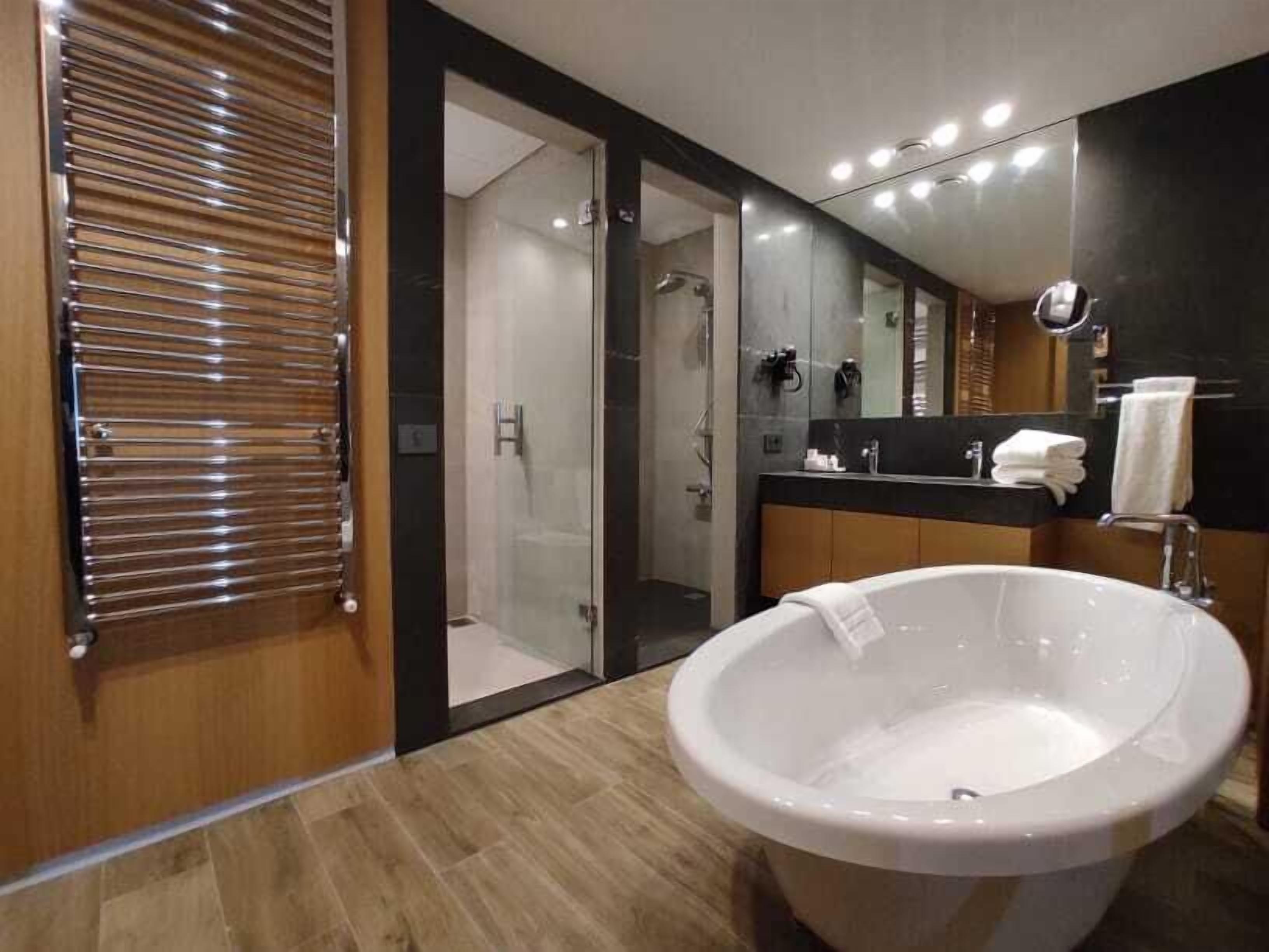 A modern bathroom with a large bathtub, a glass shower enclosure, and a vanity with a mirror.