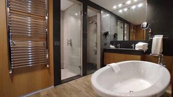 A modern bathroom with a large bathtub, a glass shower enclosure, and a vanity with a mirror.