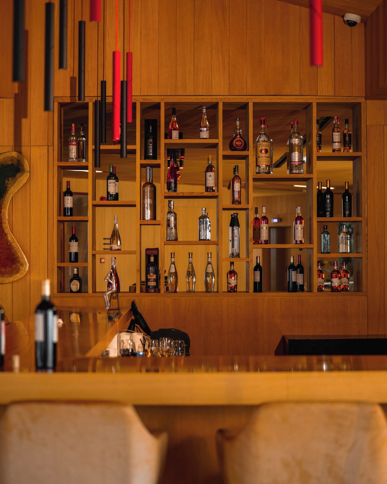 A bar area with shelves of various liquor bottles, a bar counter, and a wooden wall.