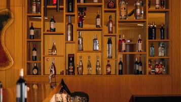 A bar area with shelves of various liquor bottles, a bar counter, and a wooden wall.