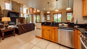 A spacious kitchen with a stone fireplace, wooden cabinets, and a large island with a sink. - Dog Friendly Mountain Retreat w/ Hot Tub & Views (McHenry)