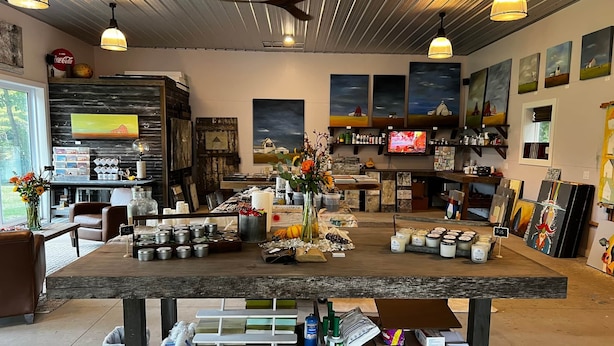 Ein rustikales Interieur mit einem Holztisch, der Kerzen und Gläser zeigt, einem Fernseher und Kunstwerken an den Wänden.