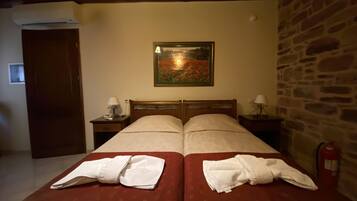 Quarto de hotel com duas camas, um quadro na parede, uma parede de pedra e um extintor de incêndio.