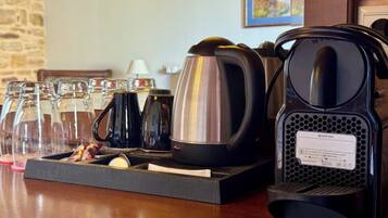 Una estación de café con una cafetera, un hervidor y varias tazas y vasos sobre una bandeja.