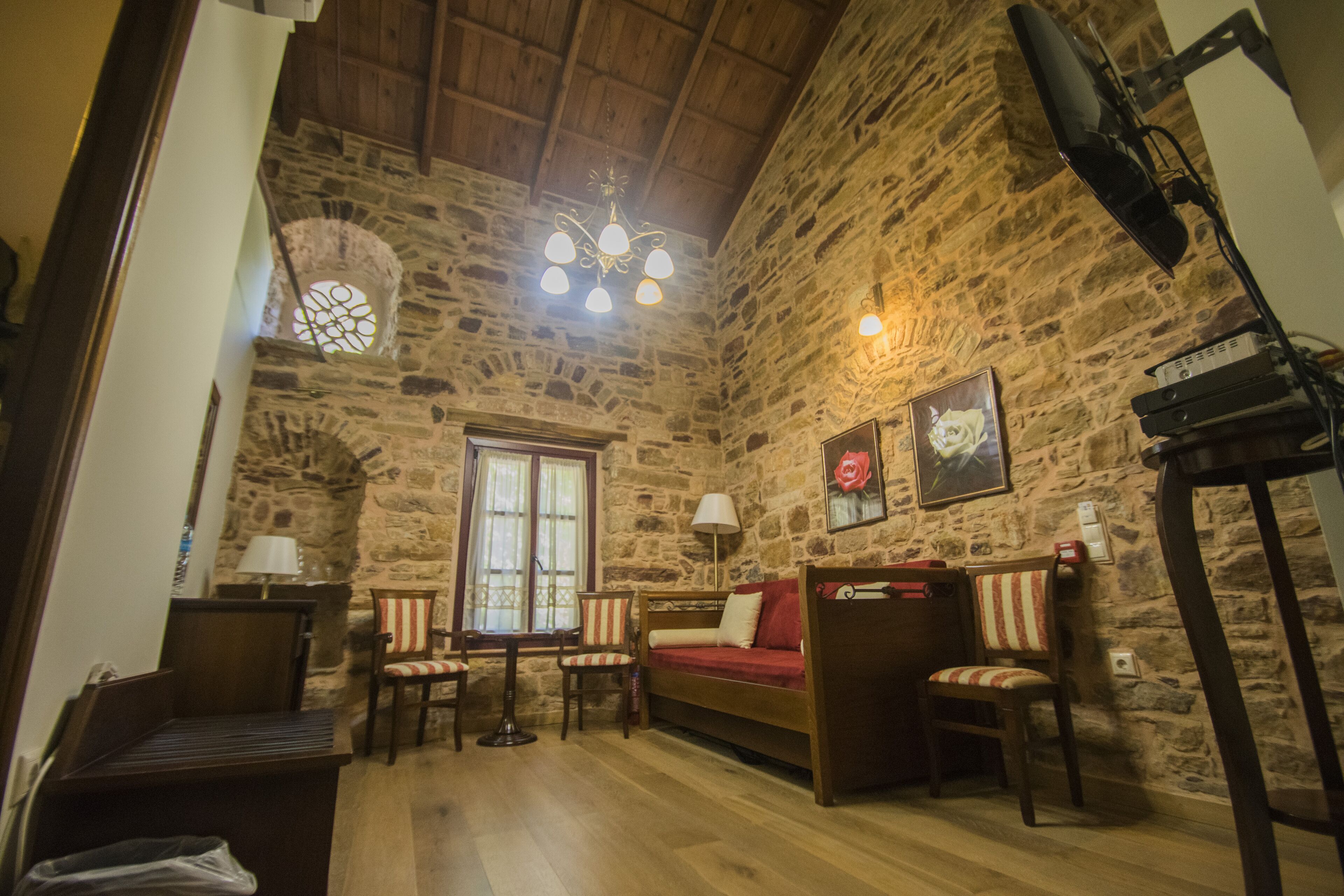 Una habitación acogedora con paredes de piedra, techo de madera, un sofá, una mesa y sillas.