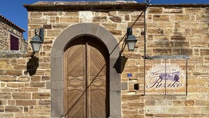 Un edificio de piedra con una amplia puerta doble de madera, un letrero que dice "Alfonso Hotel" y un suelo empedrado de piedra.
