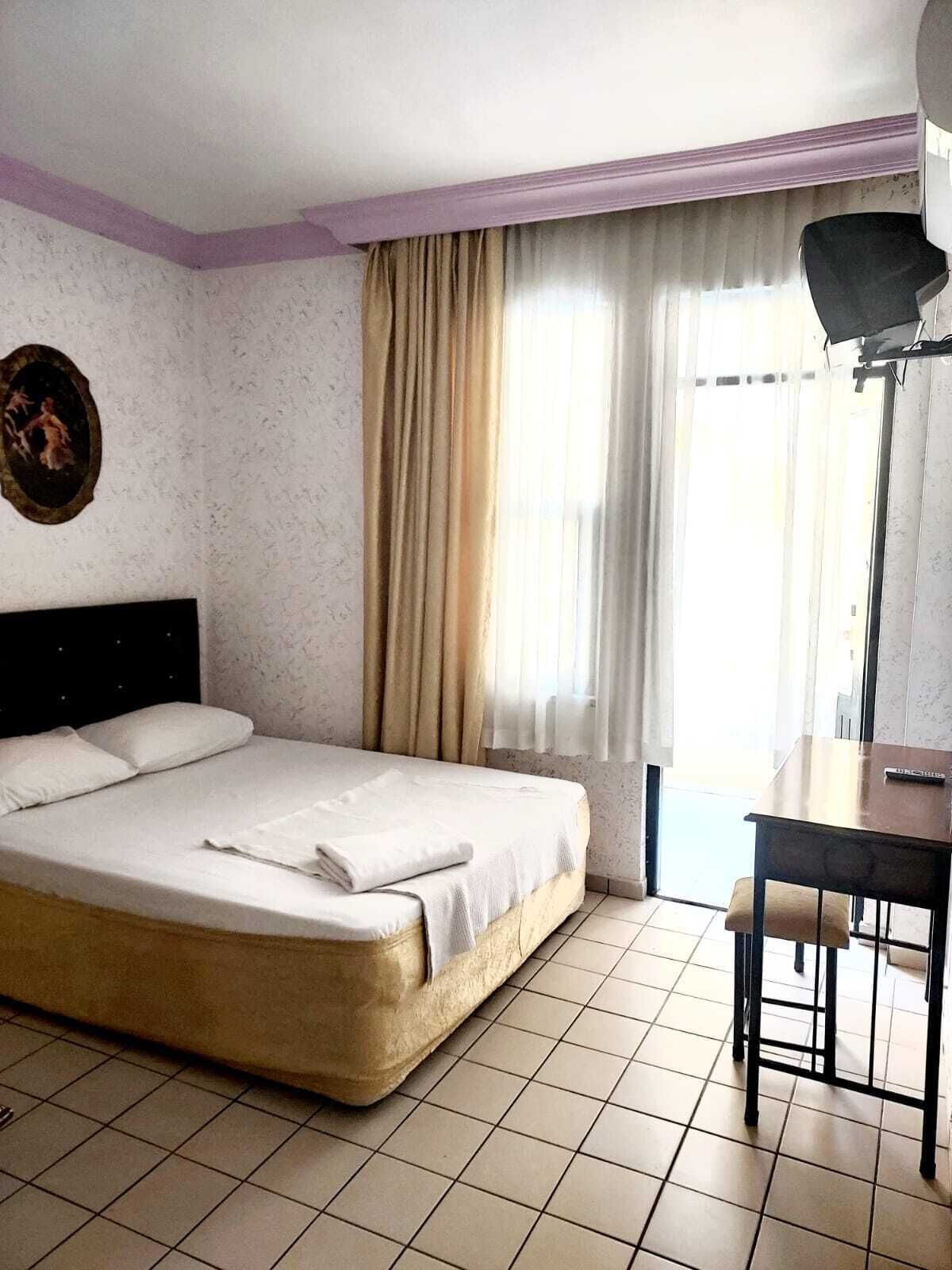 Een hotelkamer met een bed, bureau en raam met gordijnen.