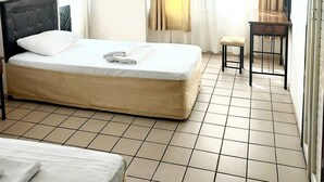 Habitació d'hotel amb un llit, una taula petita, una cadira, un televisor fixat a la paret i una finestra amb cortines.
