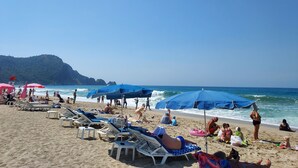 Platja amb gandules, ombrelles i persones relaxant.