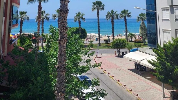 Un hotel a la costa amb vistes al mar, palmeres i un passeig pavimentat.