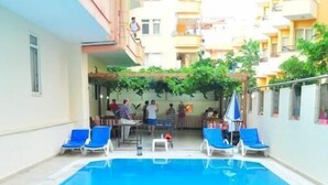 Una piscina interior amb aigua blava, envoltada de gandules blaves i una taula petita amb seients.