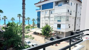 Edifici d'àmples finestrals amb balcons, zona d'aparcament i vista al mar.