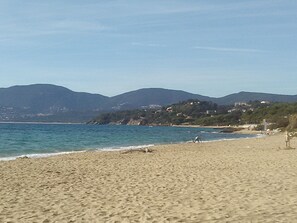 A beach with a clear view of the sea and distant mountains.