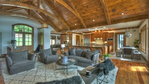 Ein geräumiges Wohnzimmer mit einem großen grauen Ecksofa, einem Couchtisch und einem flauschigen Teppich.