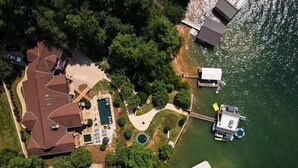 Luftaufnahme eines Anwesens am Seeufer mit Haus, Steg und Schwimmbereich.