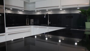 A modern kitchen with black countertops, stainless steel appliances, and a single faucet. - Luxus Apartment Pasha im Rheingau (Geisenheim)