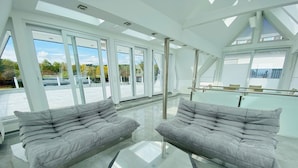 A modern, spacious room with large windows, a glass coffee table, and two grey sofas. - Luxus Apartment Pasha im Rheingau (Geisenheim)