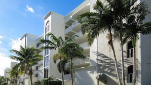 Un hotel de varios pisos con balcones, palmeras y cielo despejado.