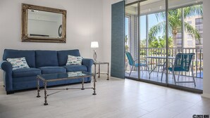 Una sala de estar moderna con un sof á azul, una mesa de centro de vidrio y un espejo grande en la pared.