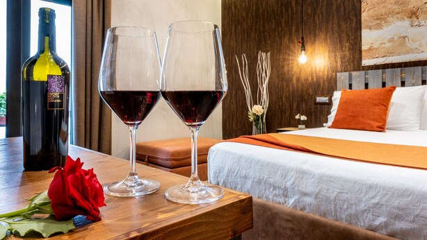 A hotel room with a wooden table, two wine glasses, a bottle of wine, and a rose. - CasaJammone Naples Bed&Breakfast (Naples)