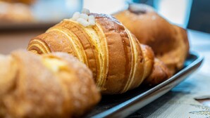 A tray of croissants with a glossy finish, likely glazed, on a metal plate. - CasaJammone Naples Bed&Breakfast (Naples)