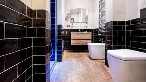 A modern bathroom with black and white tiles, a glass shower enclosure, and a white toilet. - CasaJammone Naples Bed&Breakfast (Naples)
