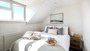 A bedroom with a bed, a nightstand, a radiator, and a window. - The Lookout Broadstairs, 3 bed 2 bath Apt, central, sea views, kids & dogs ok (Broadstairs)