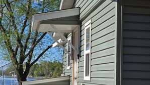 Une maison avec un porche à l’avant, une petite fenêtre et un boîtier électrique apparent.