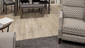Un coin repas comprenant une table, des chaises et un ventilateur de plafond. Il y a une fenêtre avec des stores et une vue sur l’extérieur.