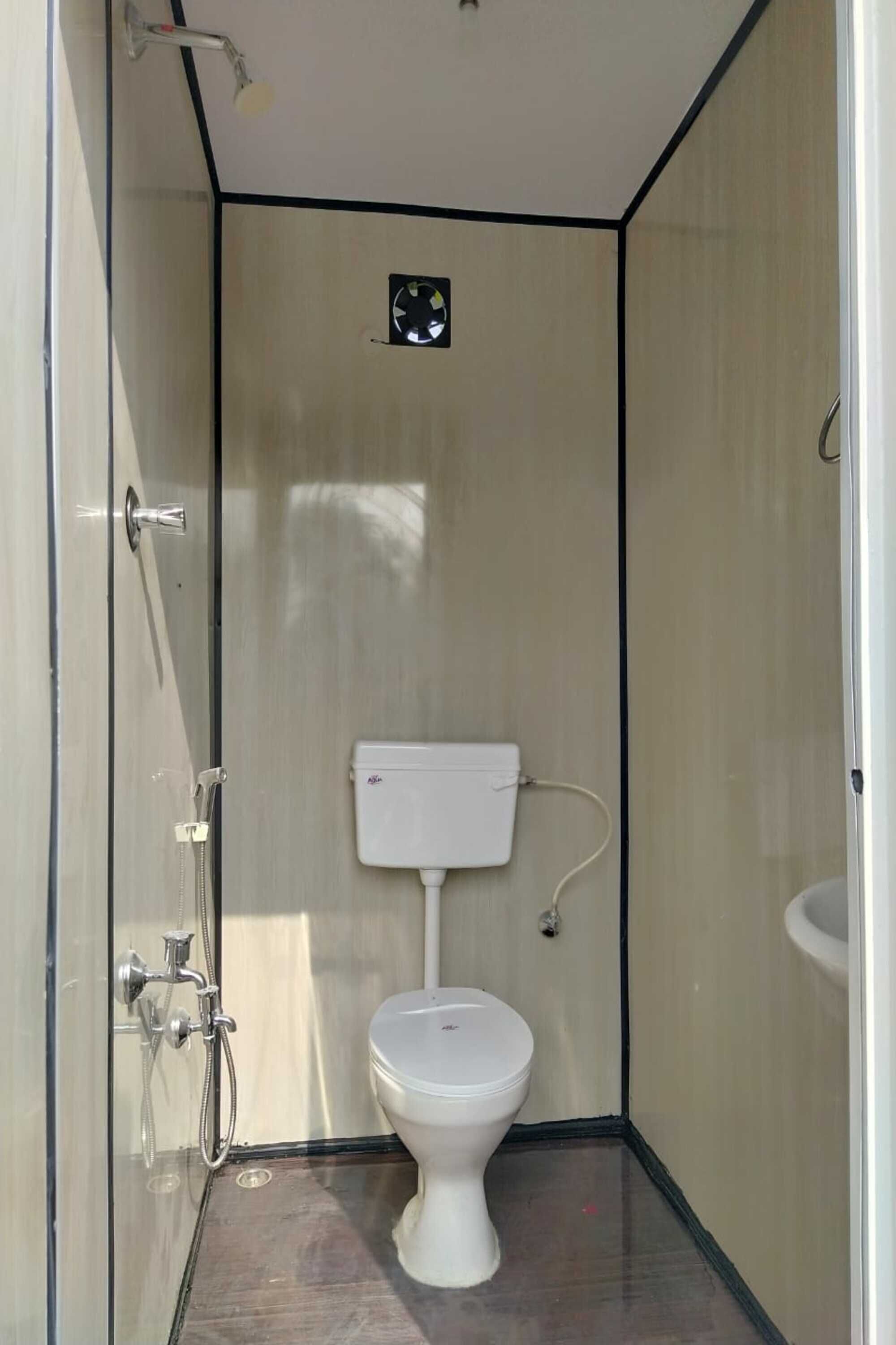 A small, enclosed bathroom with a toilet, a shower, and a sink.