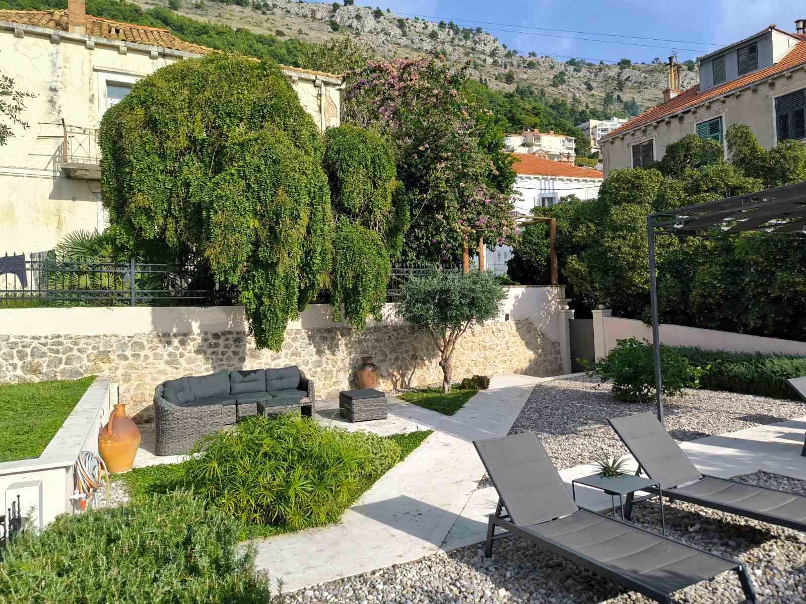 Un patio con mobiliario exterior, un muro de piedra y vistas de los edificios circundantes.