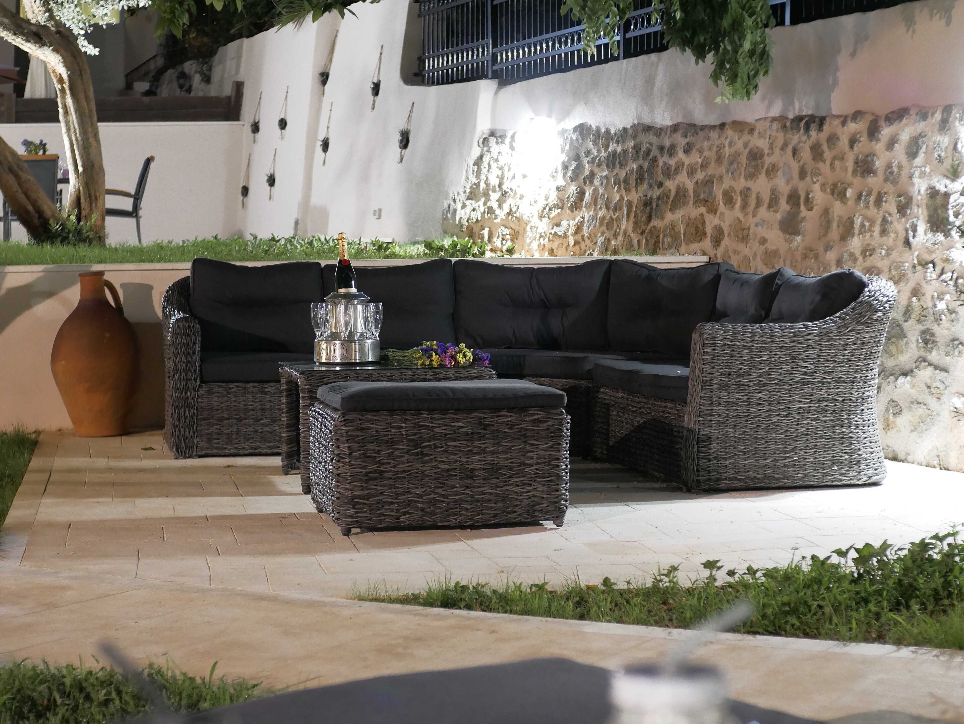 Un canapé modulable avec une table basse au plateau en verre et un pouf en osier.