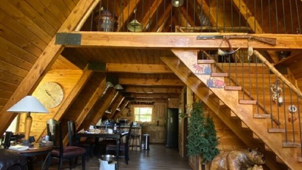 Amplia habitación en el ático con escalera de madera, zona de comedor y una acogedora chimenea.