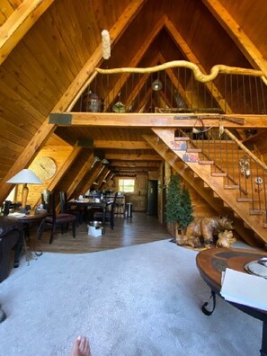 Une pièce mansardée spacieuse avec un escalier en bois, un coin repas et une cheminée accueillante.