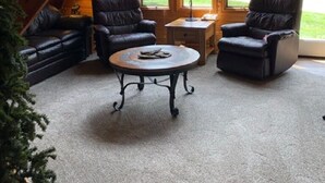 Una sala de estar acogedora con chimenea, sillones de cuero, una mesa de centro y una escalera que sube a un nivel superior.