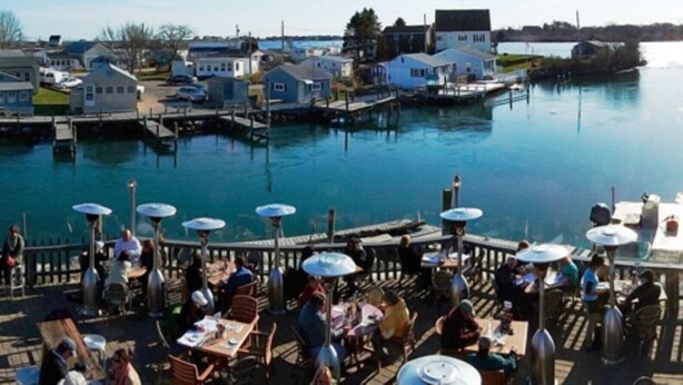 A waterfront restaurant with outdoor seating and a view of the water.