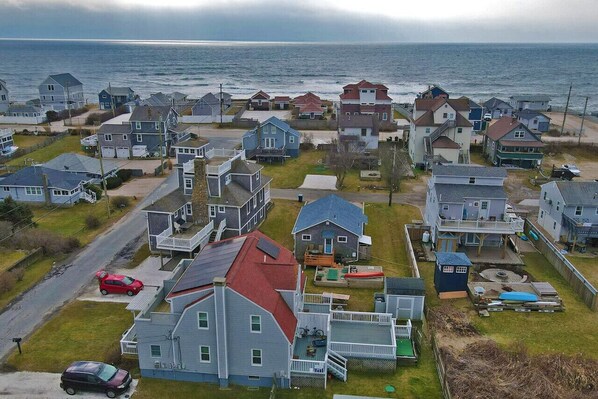 A coastal residential area with houses, a road, and a view of the ocean.