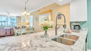 A modern kitchen with a marble countertop, stainless steel sink, and a coffee maker.