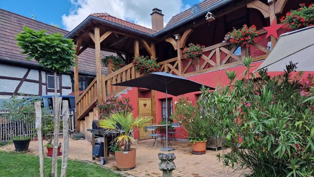 Een traditioneel vakwerkhuis met een overdekt terras, buiten zitplaatsen en potplanten.