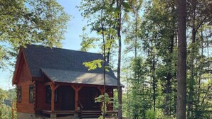 A rustic cabin with a sloped roof, wooden exterior, and a porch. - Persimmon - Hand hewn private log cabin with views (Logan)
