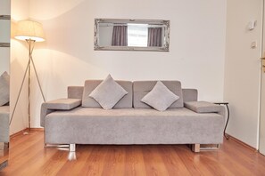 A modern living room with a grey sofa, two cushions, a floor lamp, and a mirror on the wall. - Modern Apartment in The Heart of Vienna 1 (Vienna)