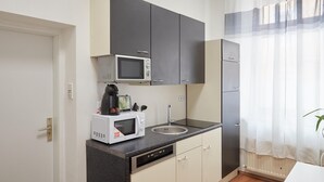 A compact kitchen with a microwave, sink, and cabinets. - Modern Apartment in The Heart of Vienna 1 (Vienna)
