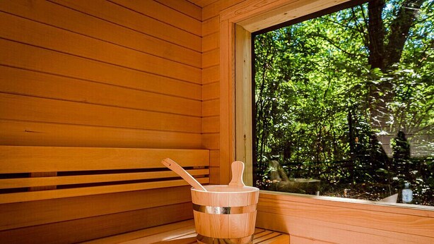 Eine Holzsauna mit Holzeimer und einer Holzbank.