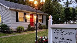 A house with a sign stating "All Seasons at Cedar Lake Vacation Rental." -  Come,Stay a While-WYNN Hosp.,Nexus Center,Cooperstown,Utica,Herkimer, Old Forge (Clayville)